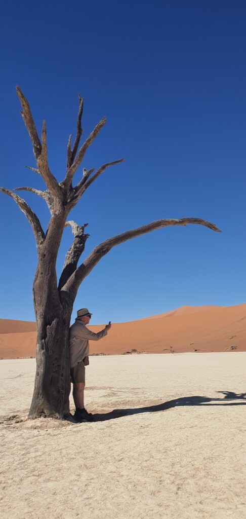 David Marshall standing beside a fossilised camelthorn tree in Deadvlei, Namibia, photographed by Natasha Isabelle.